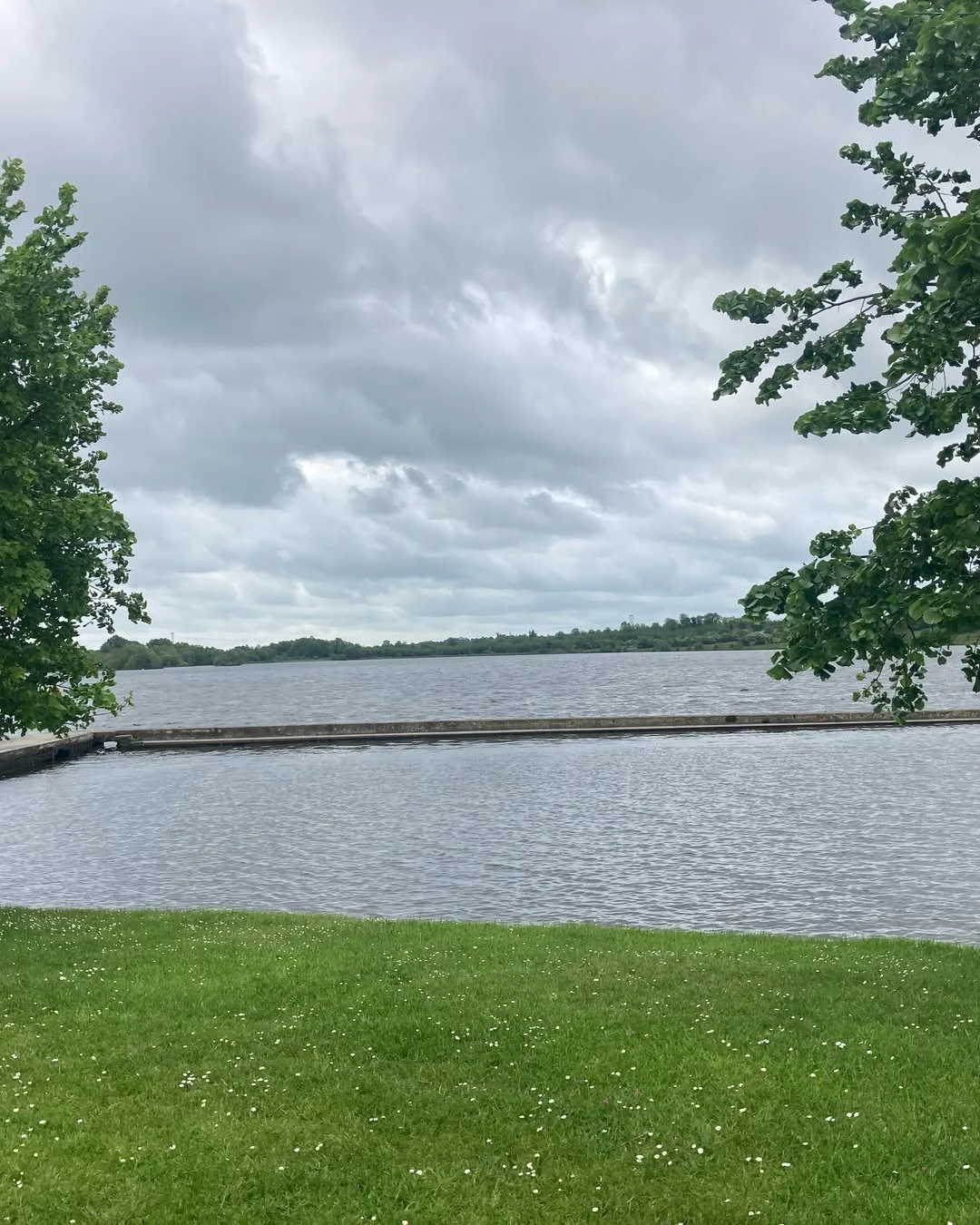 Keeldra Lake framed by green trees, with the bathing pier stretching across the water